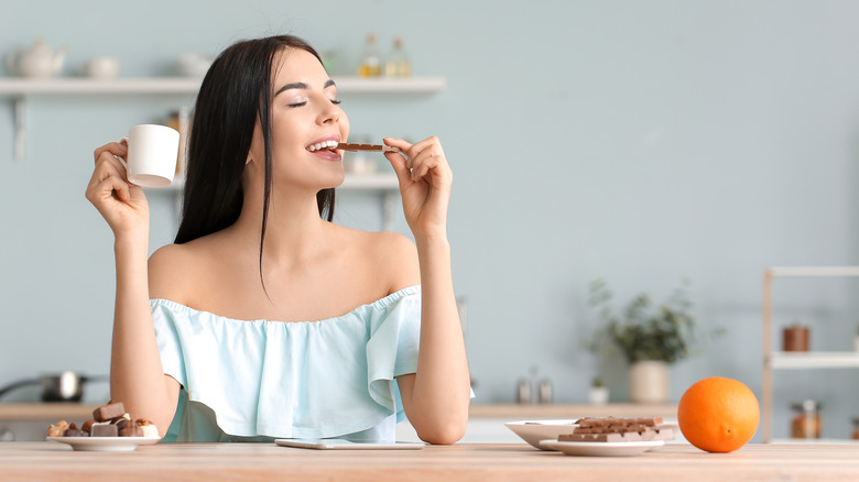 A woman enjoys a bar of chocolate