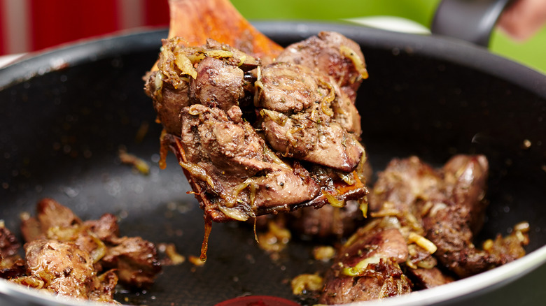 Woman cooking chicken liver in a skillet 