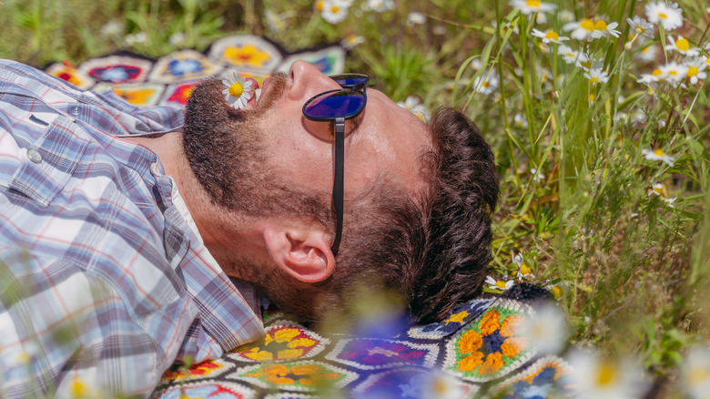 Bearded man lying in a field with flowers - pollen concept