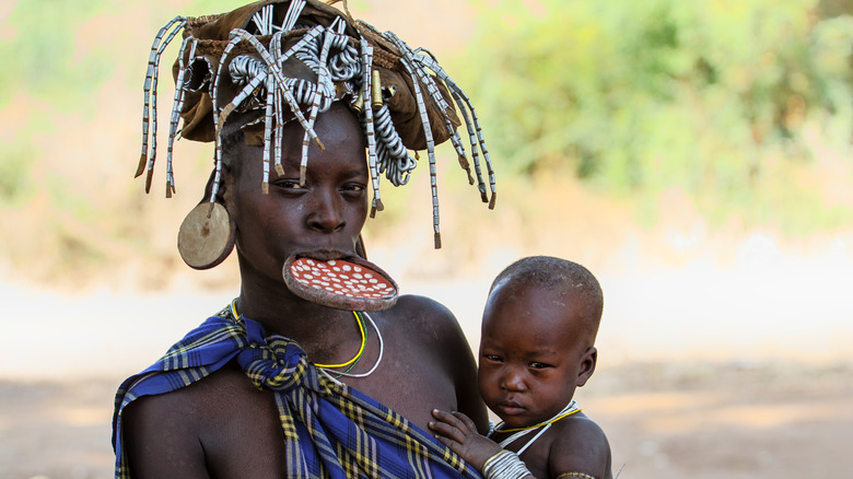 Mursi woman with lip plate, carrying baby