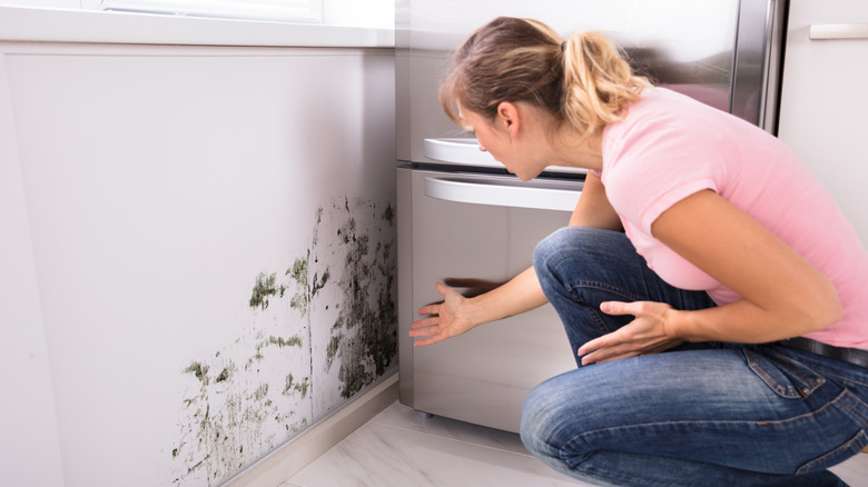 A woman looks at mold in her kitchen