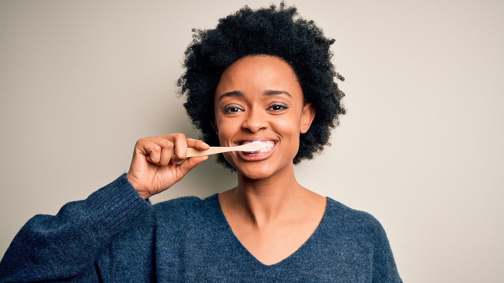 Young woman smiling while brushing her teeth 