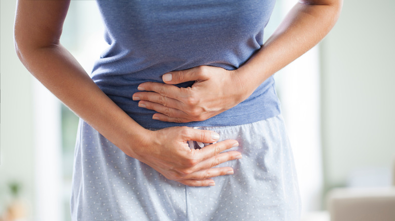 A woman holding her stomach in discomfort