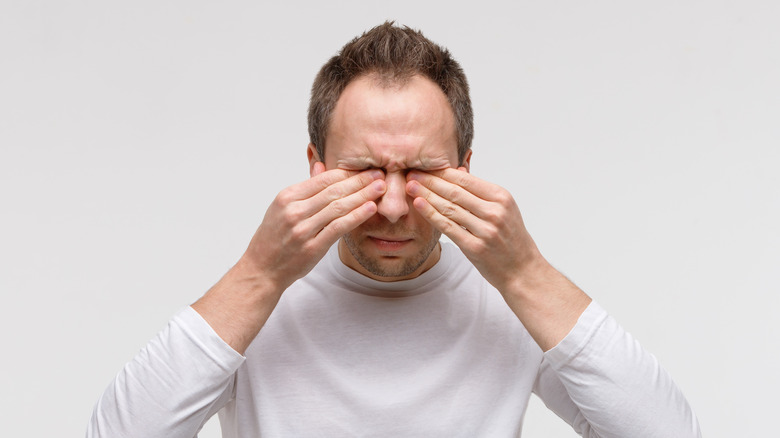 close up of a man rubbing his eyes 