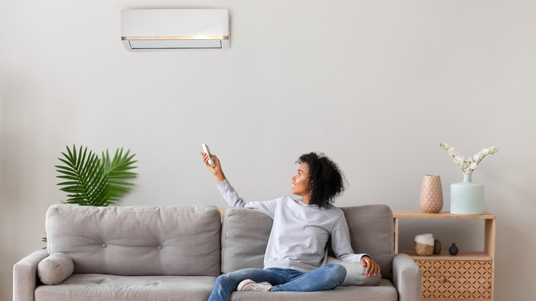 Woman turning on air conditioning 