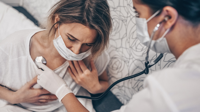 A healthcare professional listens to a woman's breathing