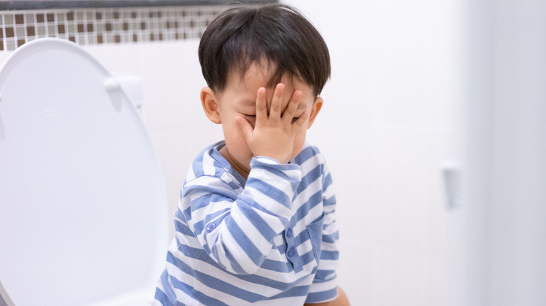 little boy face-palming on the toilet