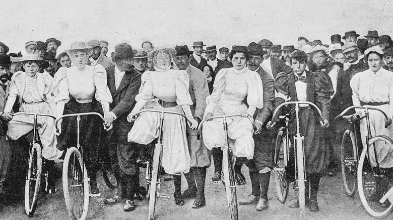 Group of women on bikes standing in front of men