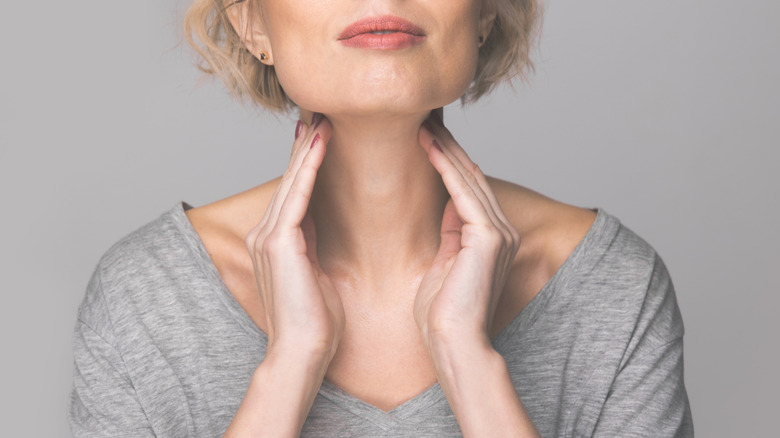 Woman touching thyroid gland