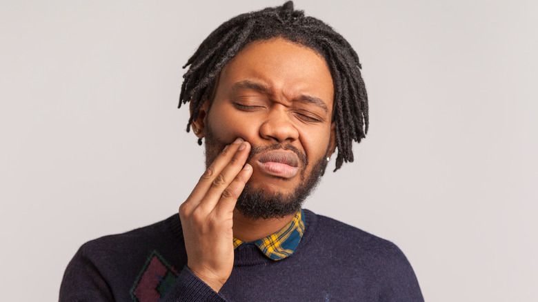 man holding cheek in pain