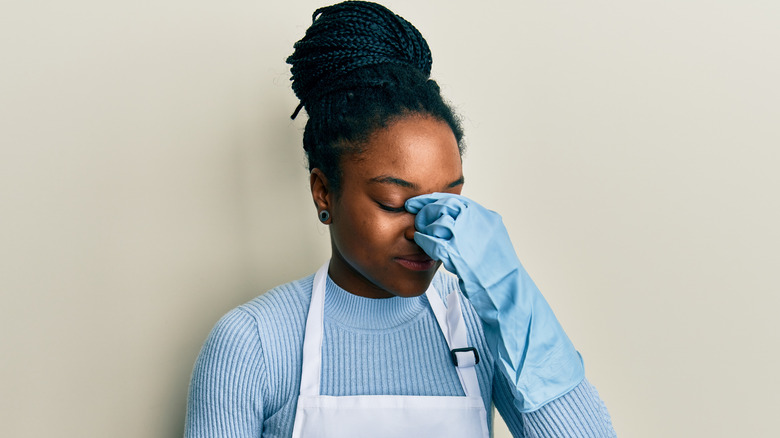 woman wearing rubber gloves, pinching bridge of nose