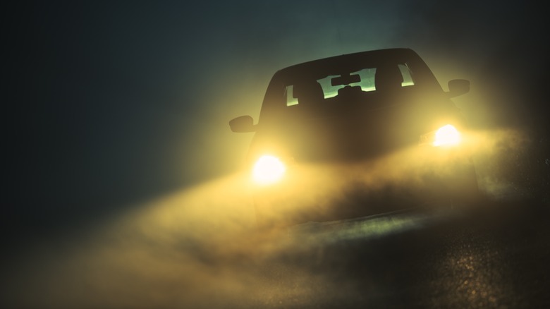 A car's headlights reflecting off fog at night