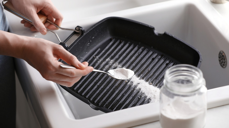 Woman using baking soda to clean grill pan
