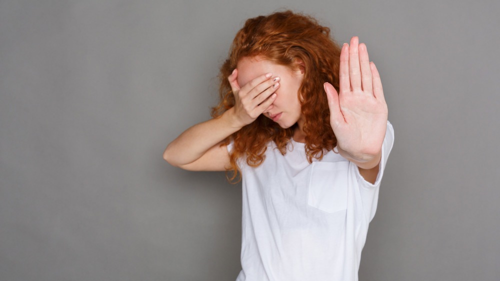 Redheaded woman covering eyes with hand