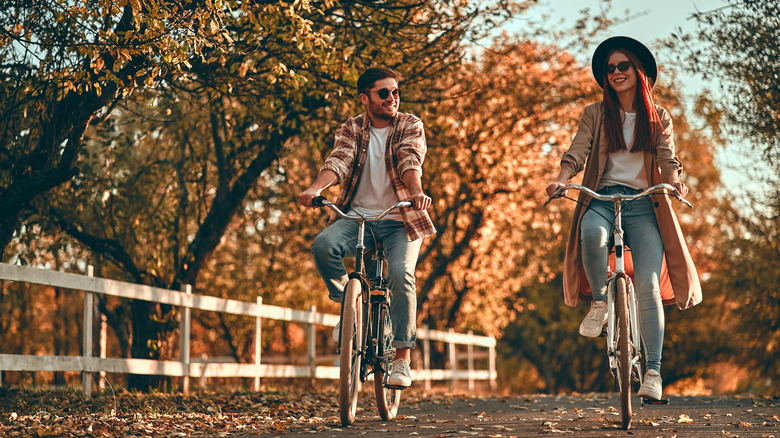 young couple riding bikes autumn