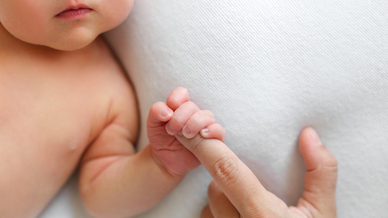 Baby holding mother's finger