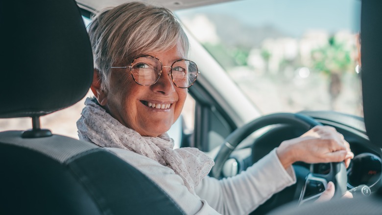 Older smiling woman driving car