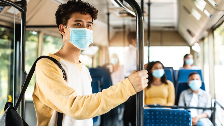 Young person and family on public transit bus wearing masks