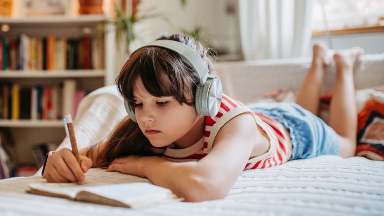 girl laying on bed listening to music and journaling