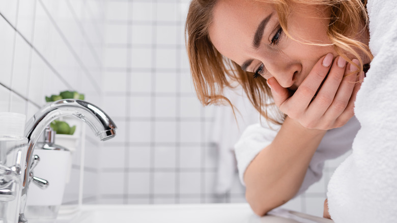 Nauseous woman leaning over a sink