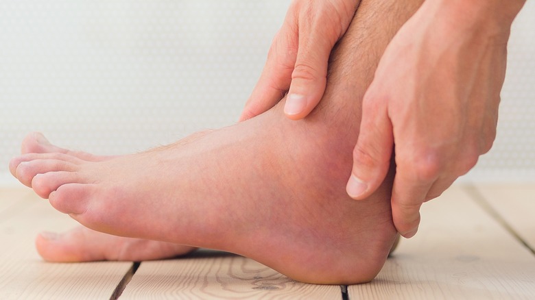 A man holding his swollen ankle