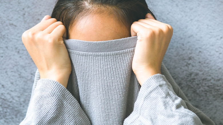 Embarrassed woman hiding in sweater