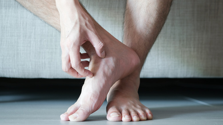 man scratching foot