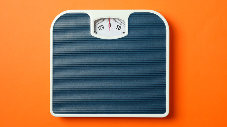 Overhead shot of a bathroom scale sitting on an orange background