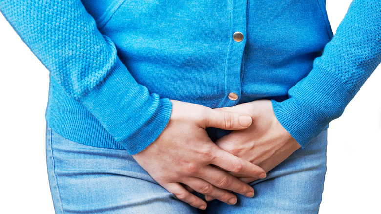 woman holding pelvic area legs crossed