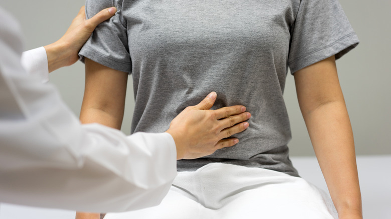 Doctor examining woman's abdomen