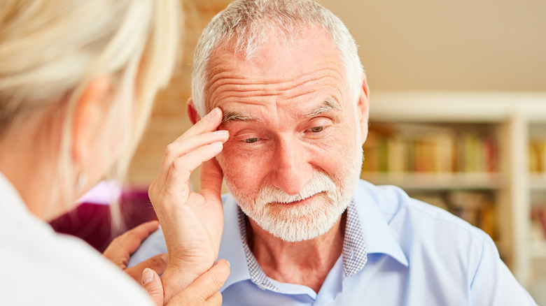 senior man with difficulty remembering being comforted by female doctor