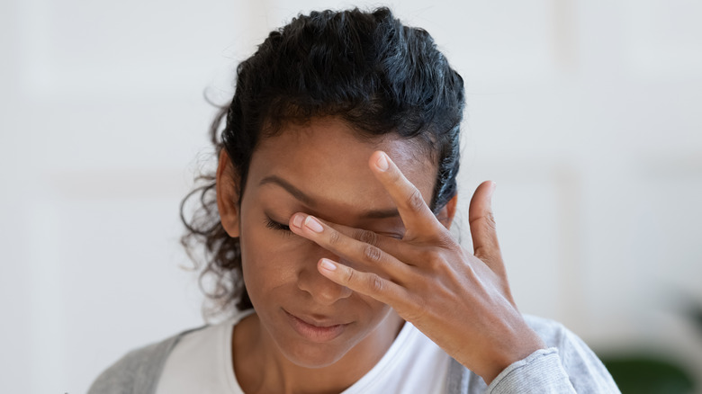 Woman with dry eyes touching face