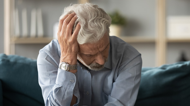 Man holding head slumped on couch