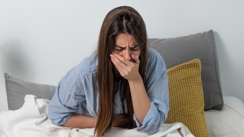 Nauseated woman sitting up in bed
