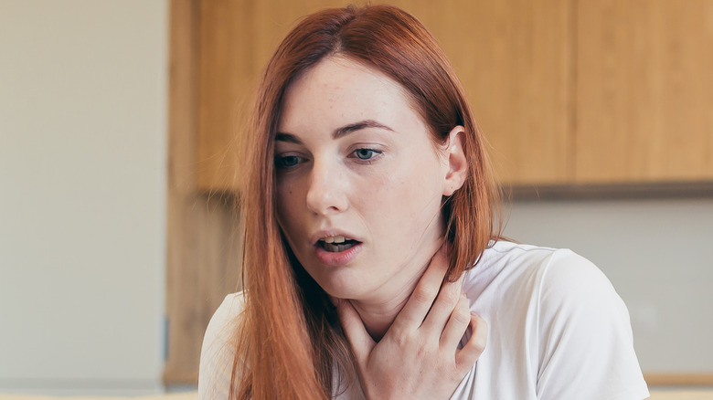 Woman touching neck having trouble breathing