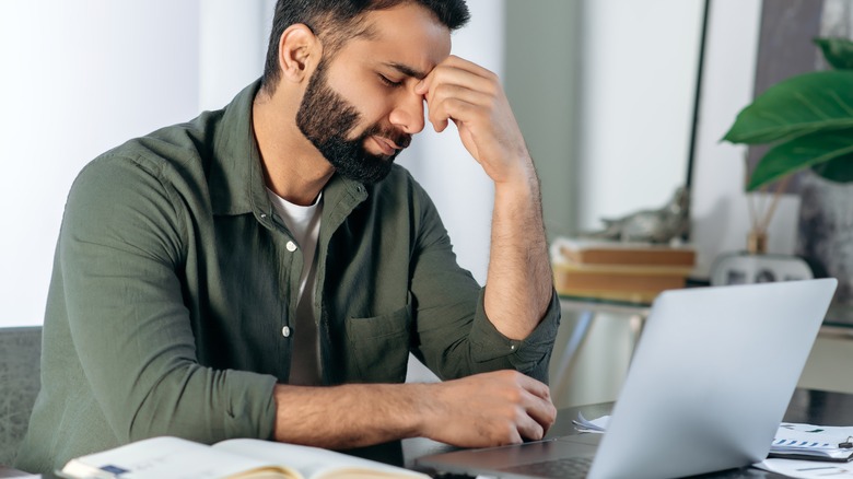 man on laptop holding head