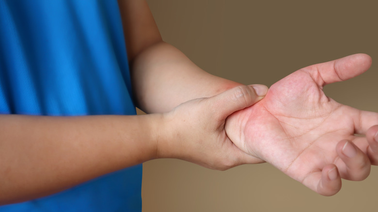 Close up of a person in a blue top holding their wrist