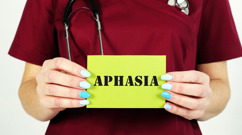 A medical professional holding up a card that says "APHASIA"