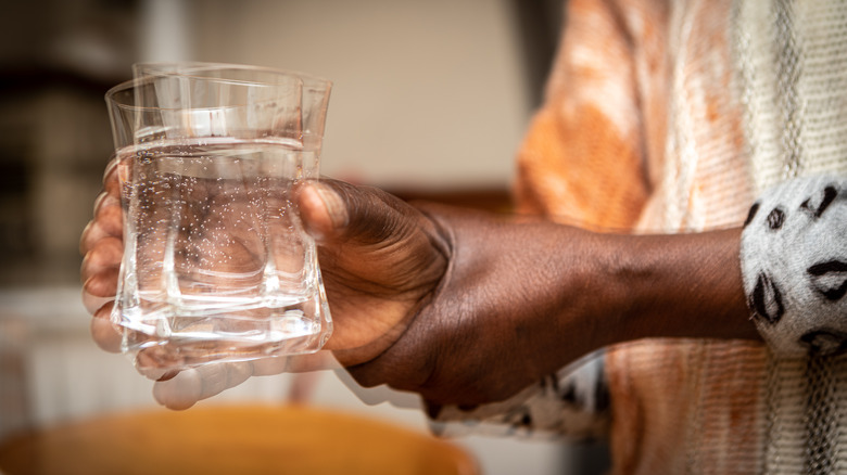 Close-up of a person's with shaking hands holding a glass