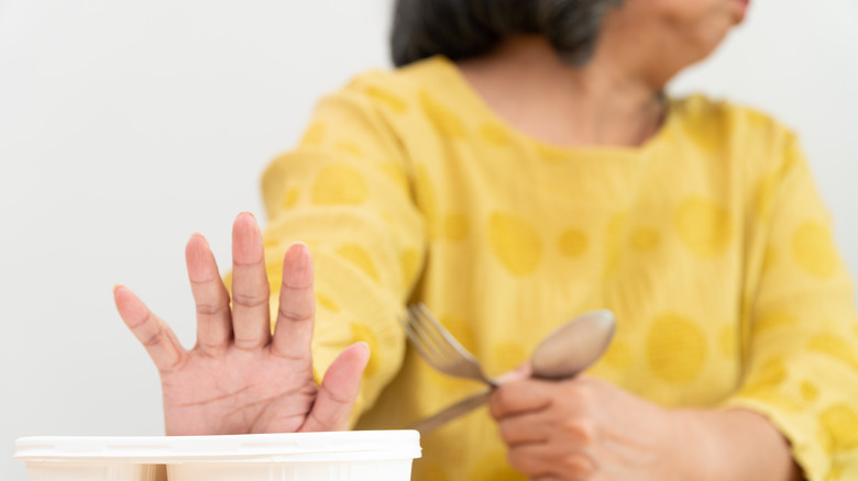 Woman pushing away helpings of food