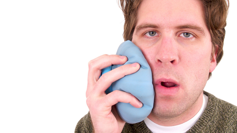 Man holding an ice pack against his cheek