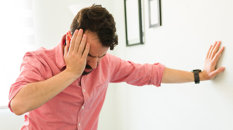 Dizzy man bracing himself against a wall