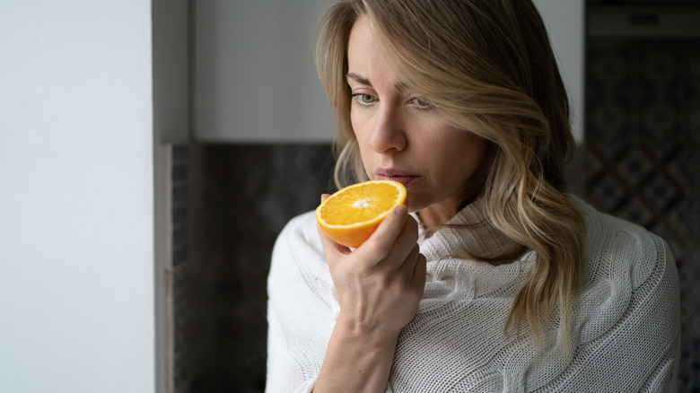 Long-haired woman smelling half an orange