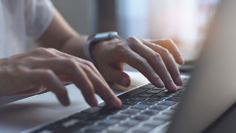 Hands typing on a laptop's keyboard