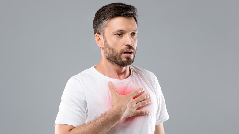 Man with a beard with his hand over his chest, which appears red