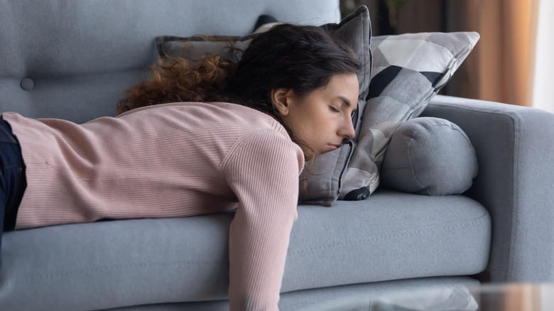 A sleeping woman in a pink shirt lying on her stomach on a cough