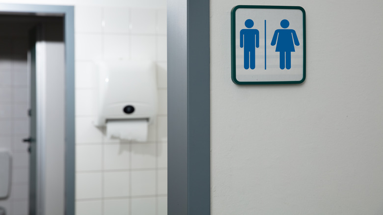 A restroom sign (with the symbols for both the men's and women's room) by the opening of a public restroom