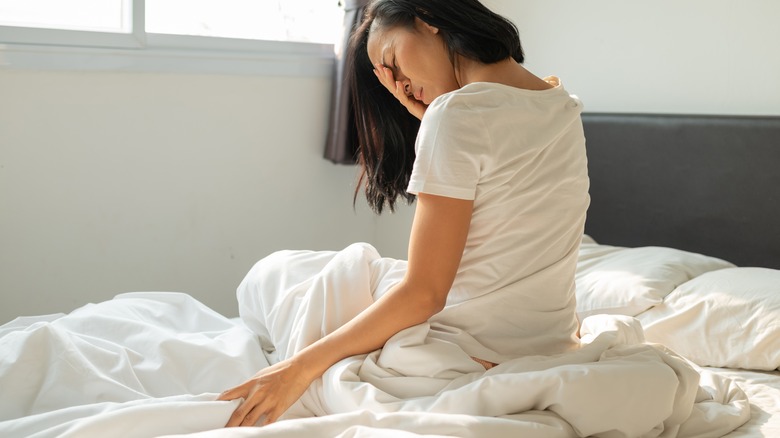 Woman with headache on bed