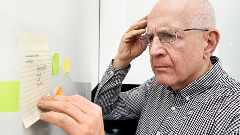 confused elderly man looking at notes 