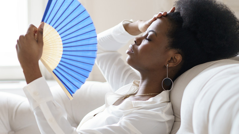 female using fan sitting on couch